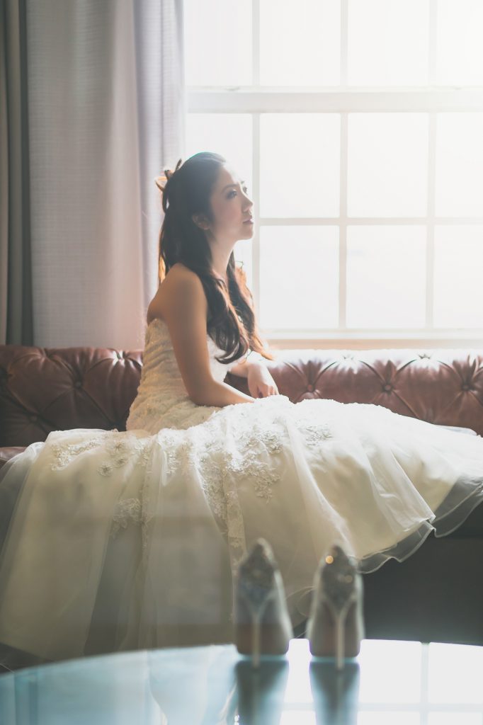 A wedding photographer, Thomas Kim, capturing a woman in her wedding dress lounging on a couch.