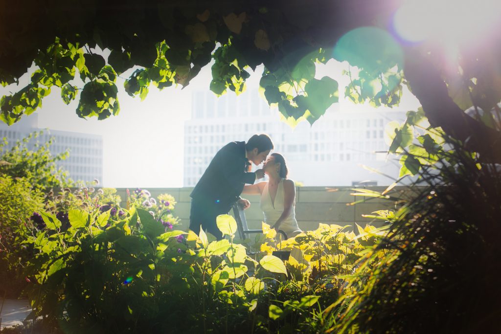 A Los Angeles wedding photographer captures the joyful moment of a bride and groom kissing under a tree in a garden.