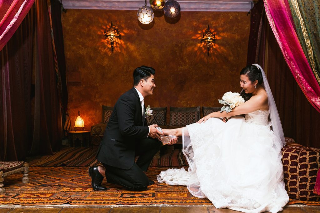 A wedding photographer captures a Los Angeles bride and groom as they put on their shoes in a room.