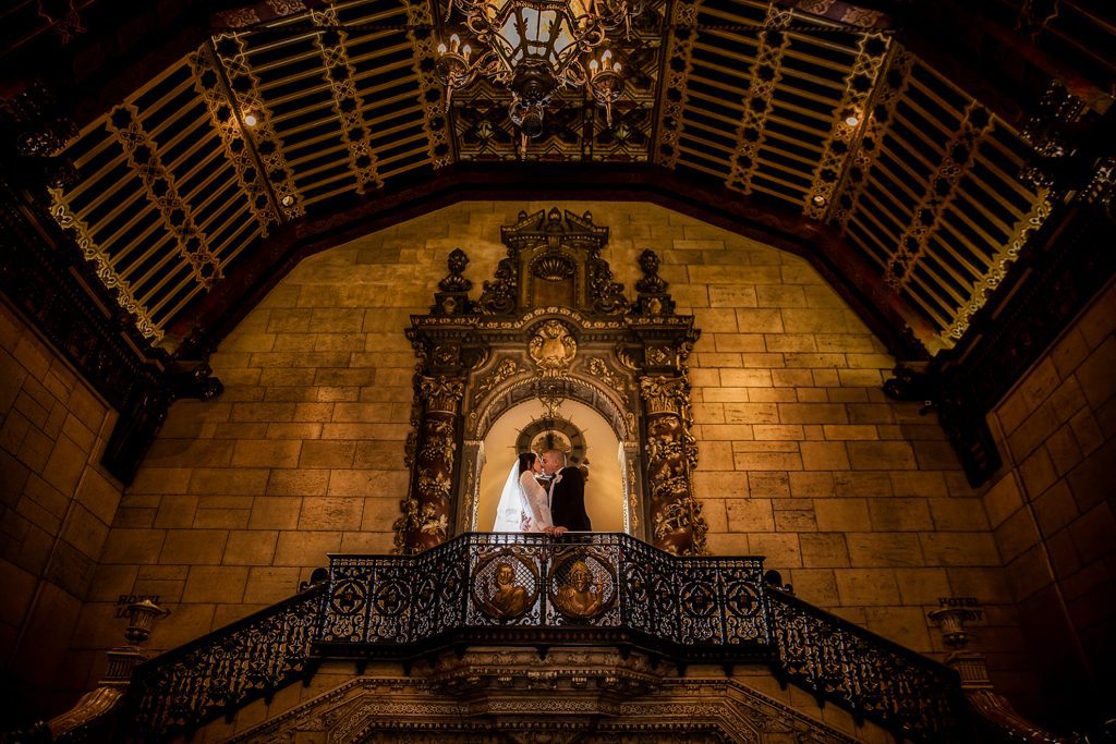 Thomas Kim, photographer captures a wedding couple on the stairs of an ornate building.