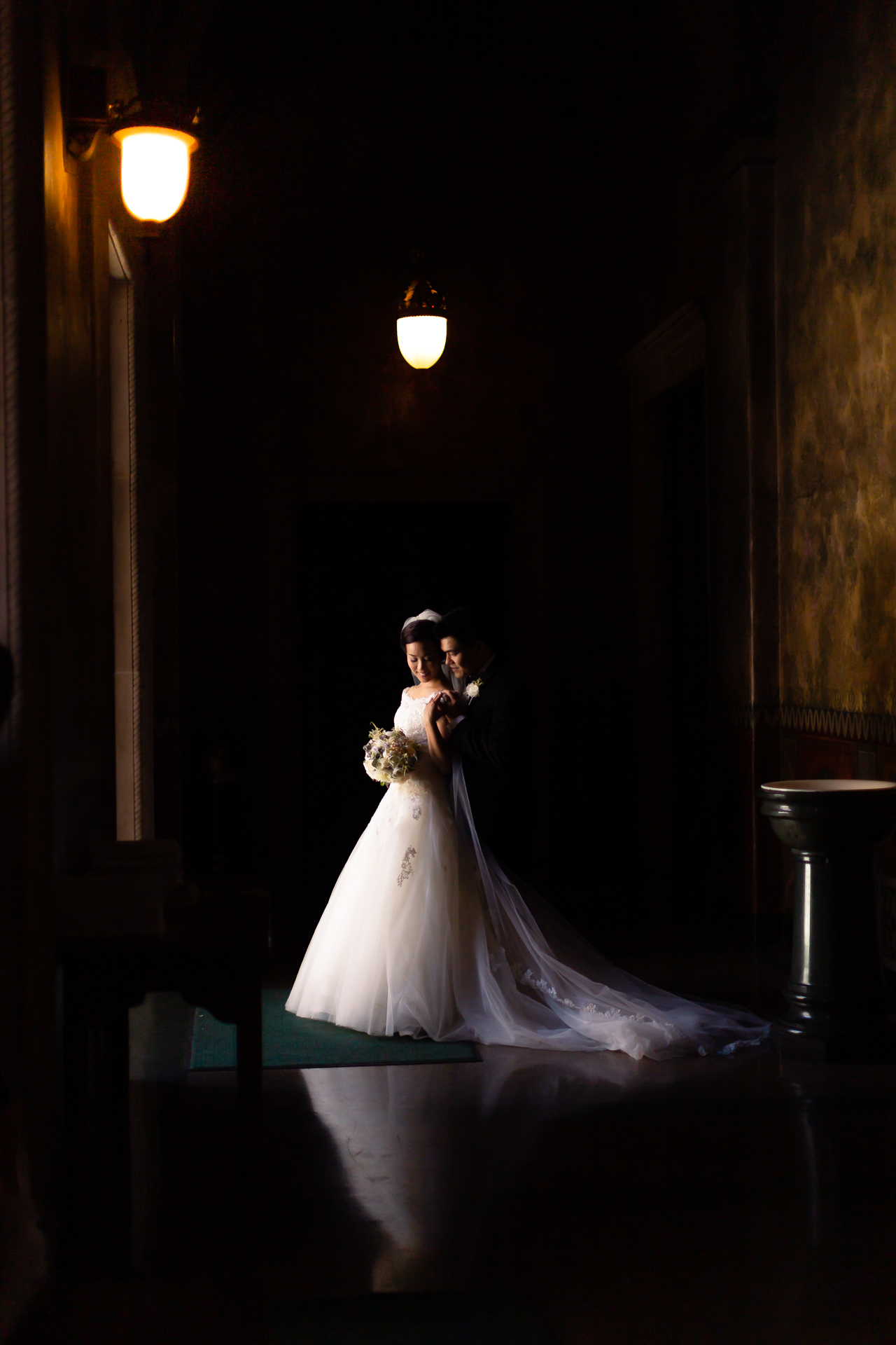 A Wedding photographer capturing Thomas Kim and the bride and groom in a dark hallway.