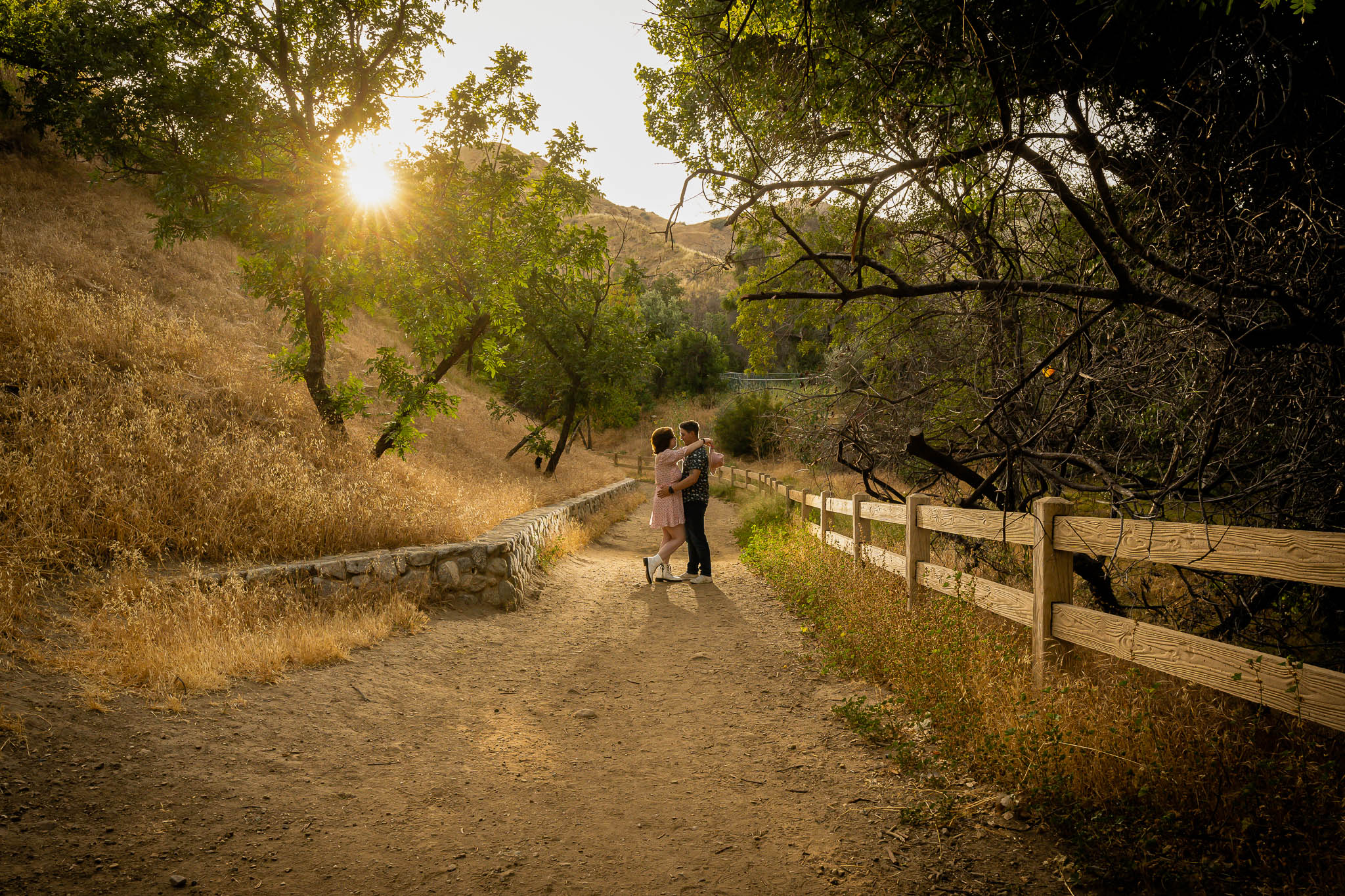 Thomas Kim, a wedding photographer, captures a couple walking down a path in a wooded area.