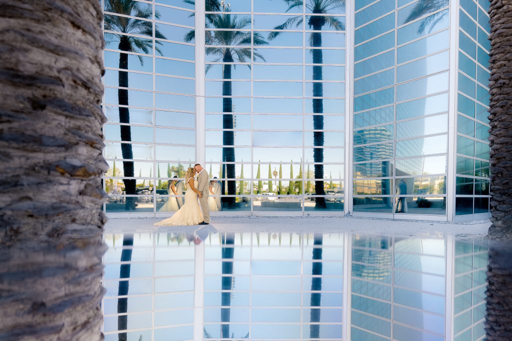 ThomasKim_photography A bride and groom, K & C, standing in front of a pool with palm trees.