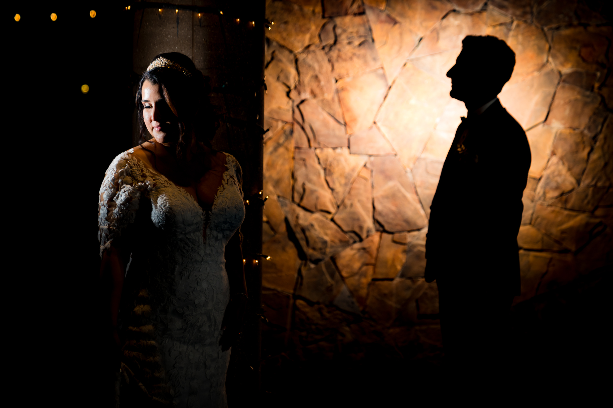 ThomasKim_photography A bride and groom posing in front of a stone wall at their wedding.
