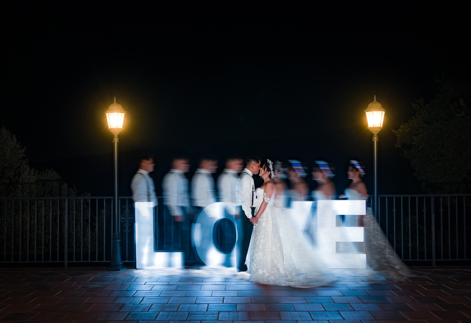 ThomasKim Photography Los Angeles Wedding Photographer A Los Angeles Wedding Photographer captures a bride and groom standing in front of a lit up love sign.