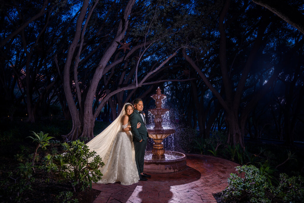 ThomasKim Photography Los Angeles Wedding Photographer A bride and groom standing in front of a fountain at night.