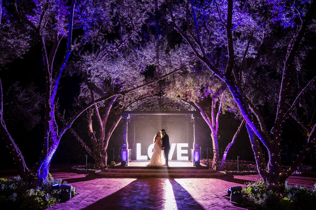 ThomasKim Photography Los Angeles Wedding Photographer A bride and groom standing in front of a lit up love sign.
