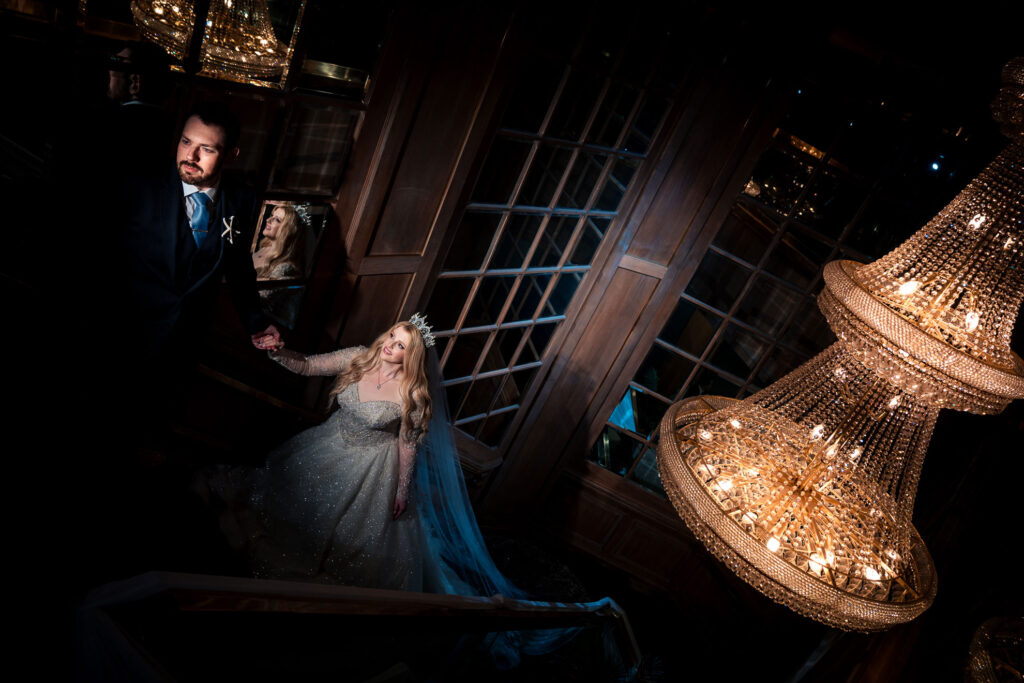 ThomasKim Photography Los Angeles Wedding Photographer A bride and groom standing in front of a chandelier, captured by a Los Angeles wedding photographer.