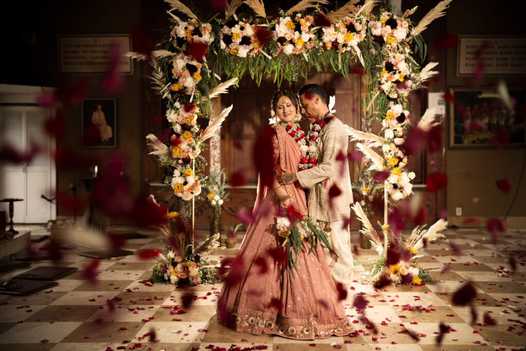 ||ThomasKim Photography Los Angeles Wedding Photographer A couple in traditional attire stands under a floral arch