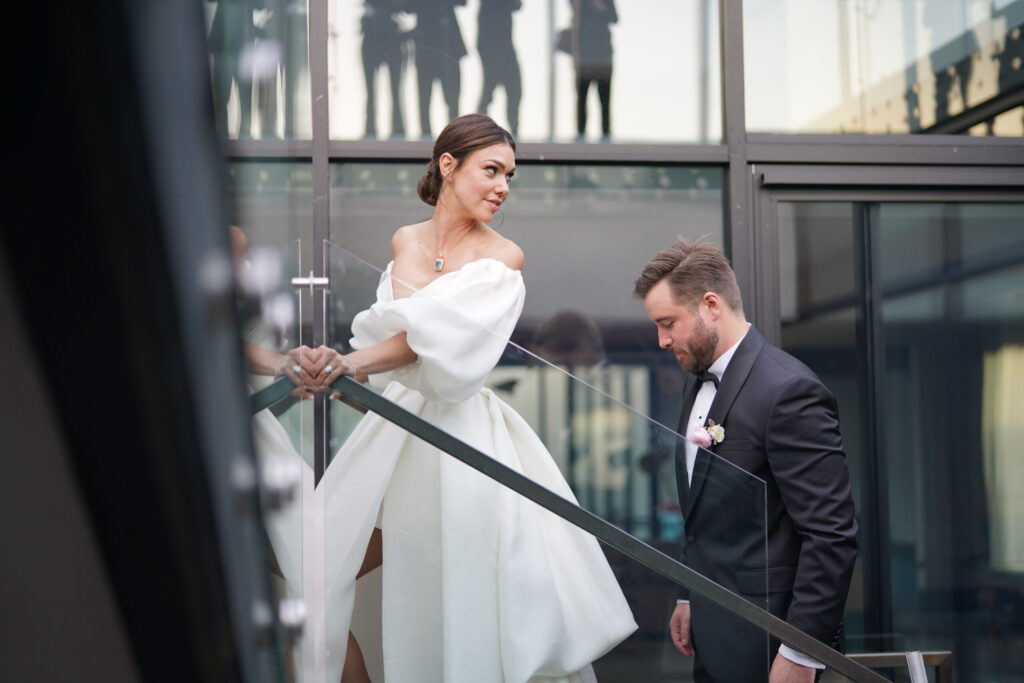 ThomasKim Photography Los Angeles Wedding Photographer A bride in a white dress and a groom in a suit descend glass stairs