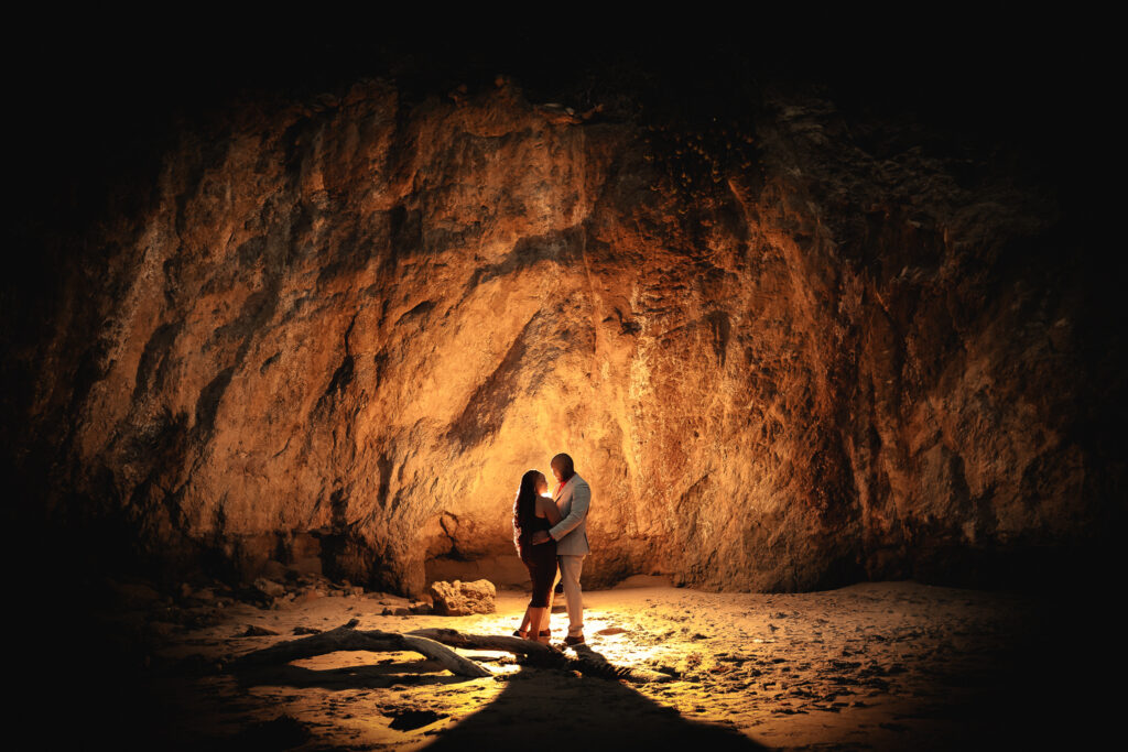 ThomasKim Photography Los Angeles Wedding Photographer Two people stand close together illuminated by a warm light against a large