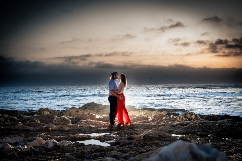 ThomasKim Photography Los Angeles Wedding Photographer A couple stands on rocky terrain by the ocean