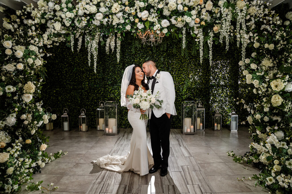 ThomasKim_photography C & A standing under a floral archway at their wedding.