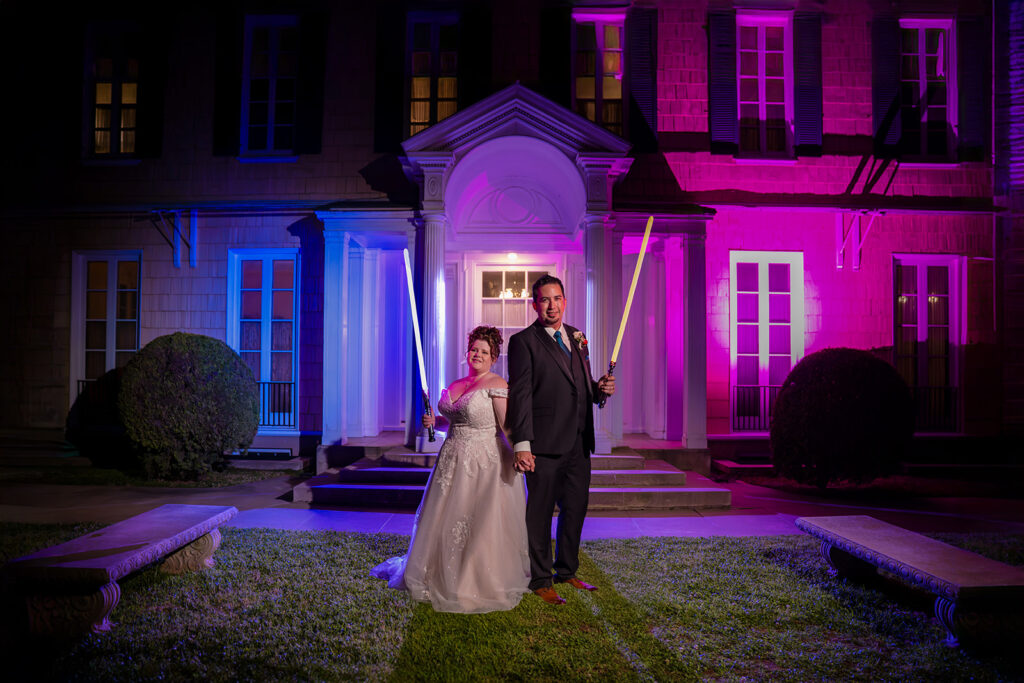 ThomasKim Photography Los Angeles Wedding Photographer A couple in formal attire stands outside a building with purple and blue lights