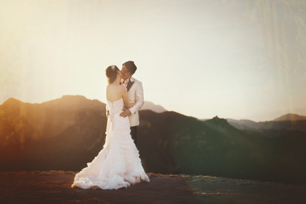 A bride and groom kissing on top of a mountain at sunset captured by Los Angeles photographer