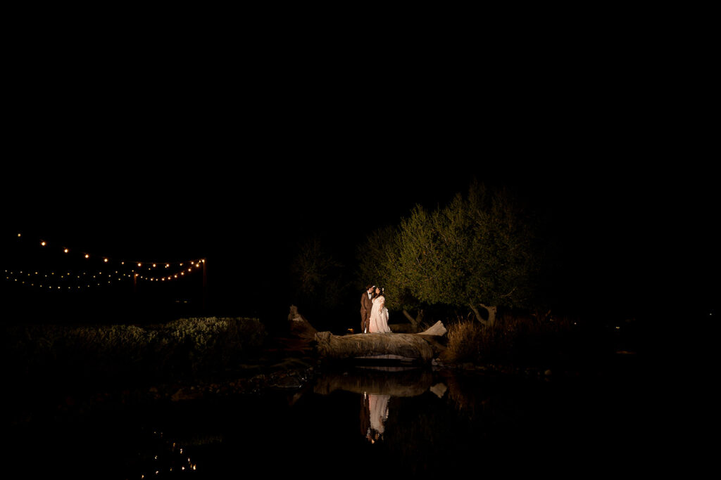 ThomasKim Photography Los Angeles Wedding Photographer A couple stands on a log near a pond at night
