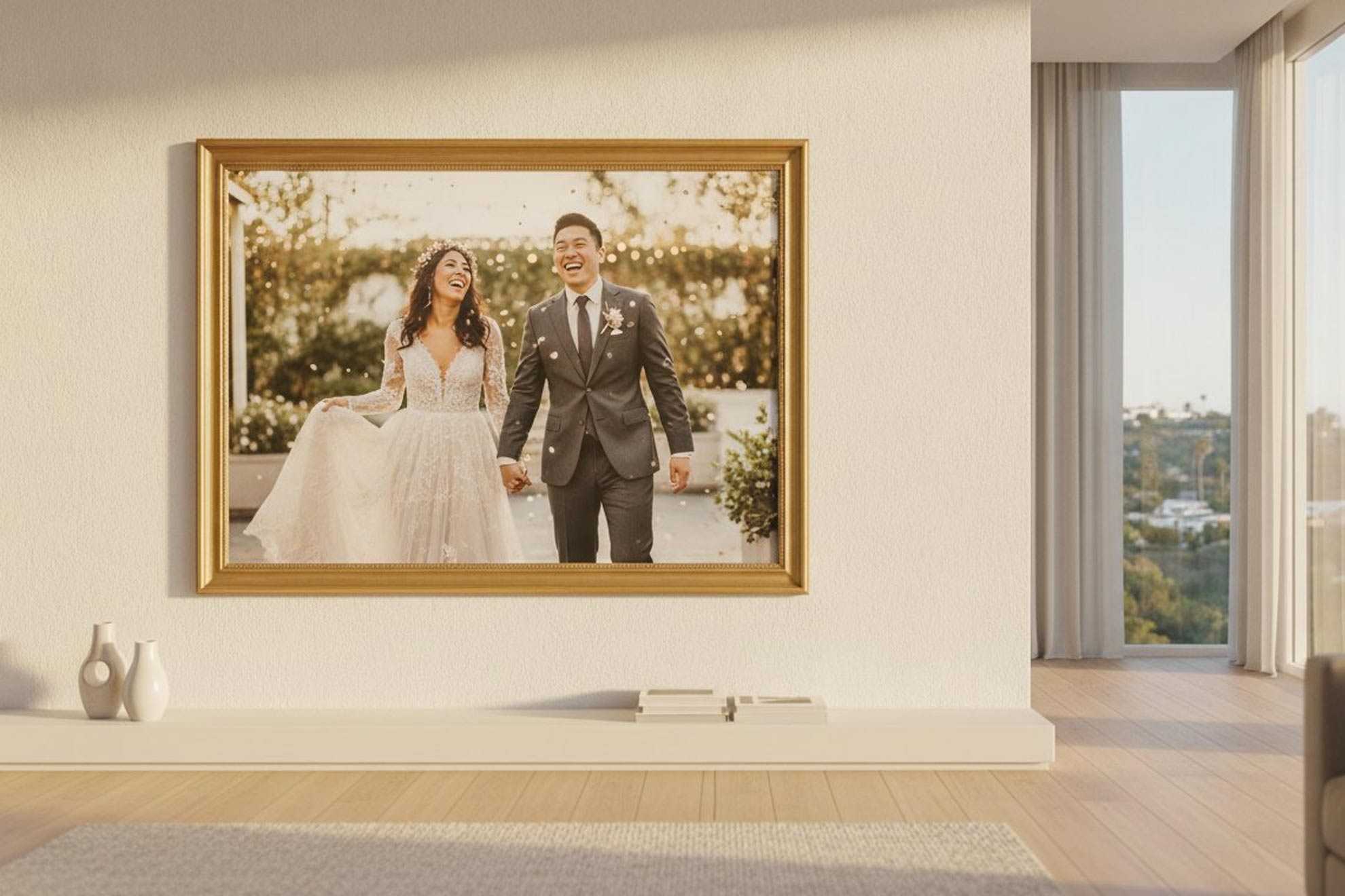 A large framed photo of a laughing bride and groom hangs on a white wall above a shelf with vases and books.
