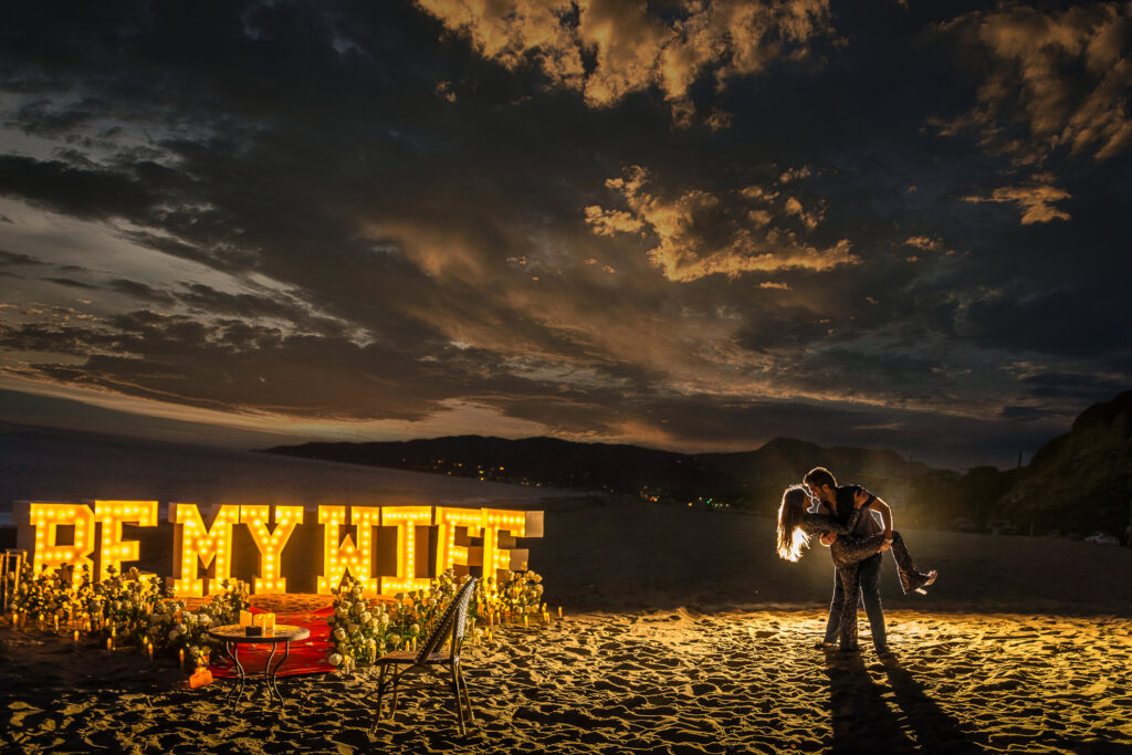 ThomasKim_photography Los Angeles Wedding Photographer captures a couple kissing in front of a sign that says be my fiance.